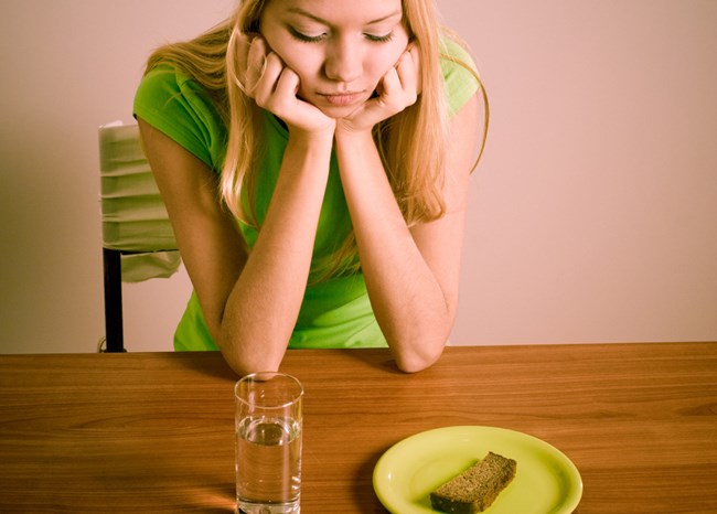 Een meisje zit voor een glas water en brood